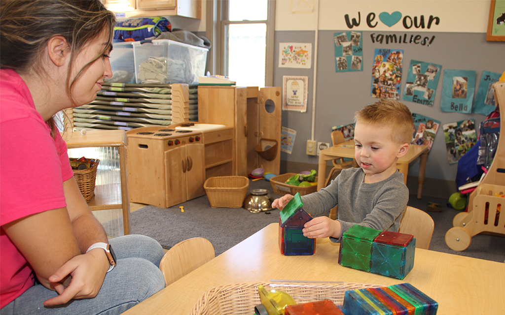 Student teacher building blocks with young child.